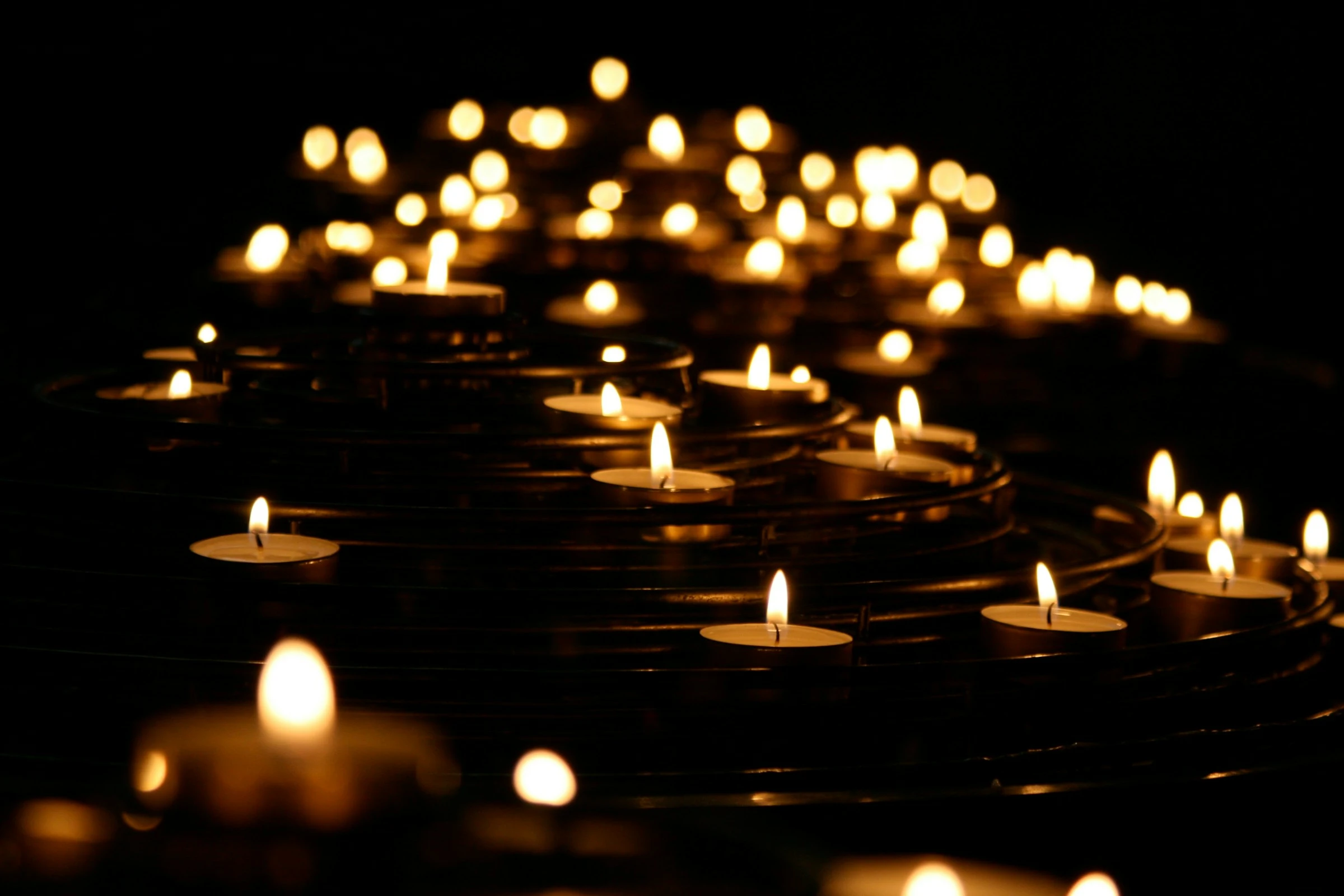 Pequenas velas acesas criam pontos de luz em um ambiente escuro.